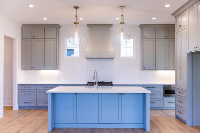 kitchen featuring light countertops, custom range hood, light wood-style flooring, and gray cabinetry