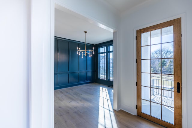 entryway with a chandelier, wood finished floors, and a decorative wall