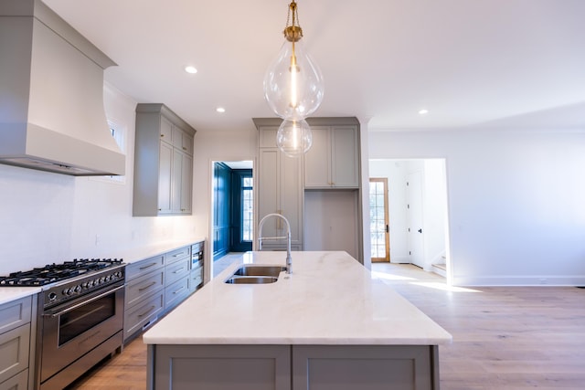 kitchen featuring custom range hood, high end stainless steel range oven, light wood-style flooring, gray cabinetry, and a sink