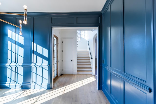 entrance foyer with light wood-type flooring, stairs, and a decorative wall