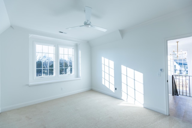 unfurnished room featuring visible vents, baseboards, carpet, vaulted ceiling, and ceiling fan with notable chandelier