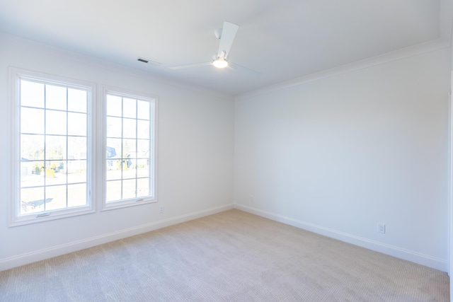 spare room featuring a ceiling fan, visible vents, crown molding, and light carpet