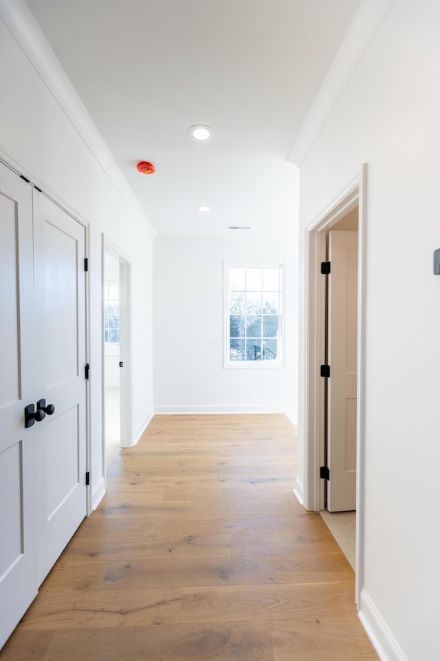 hallway featuring baseboards, recessed lighting, light wood-type flooring, and crown molding