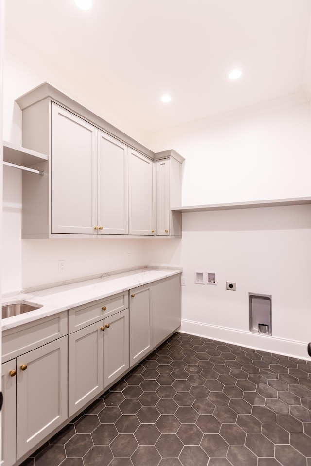 clothes washing area with cabinet space, hookup for a washing machine, hookup for an electric dryer, a sink, and recessed lighting