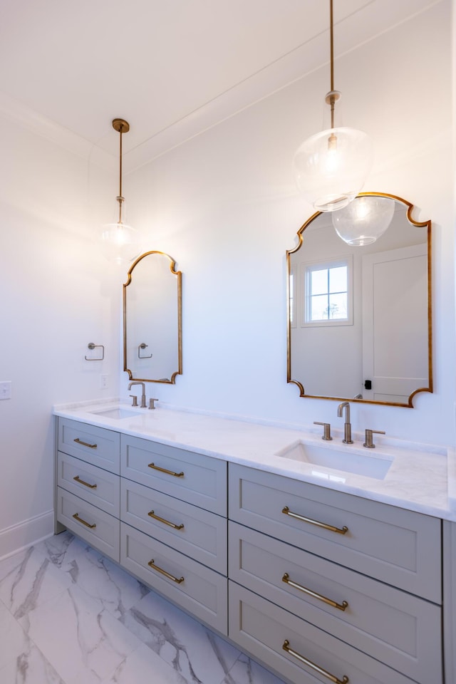 full bath featuring marble finish floor, double vanity, a sink, and baseboards