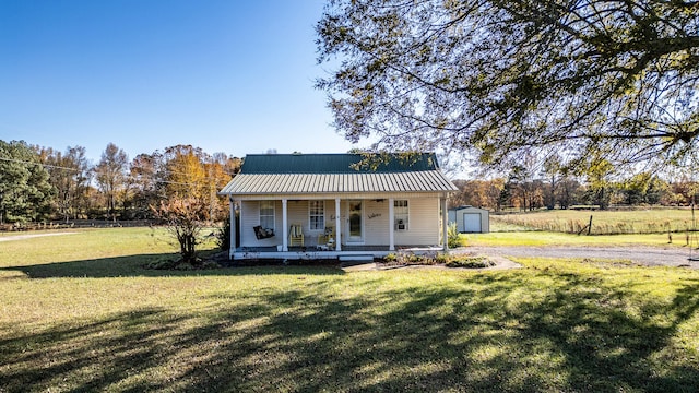 view of front of home featuring covered porch, an outbuilding, a garage, and a front yard