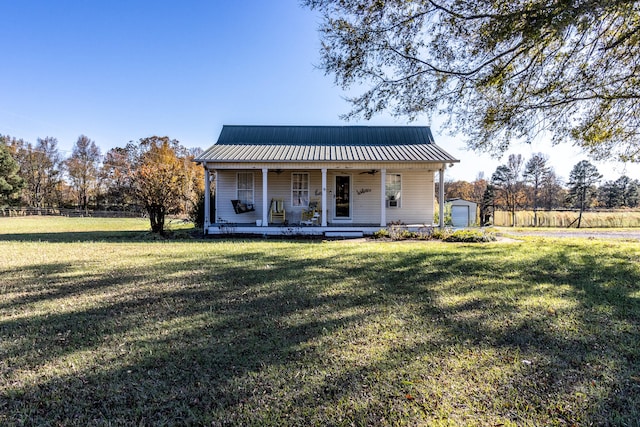 back of house featuring a porch, a garage, an outdoor structure, and a lawn