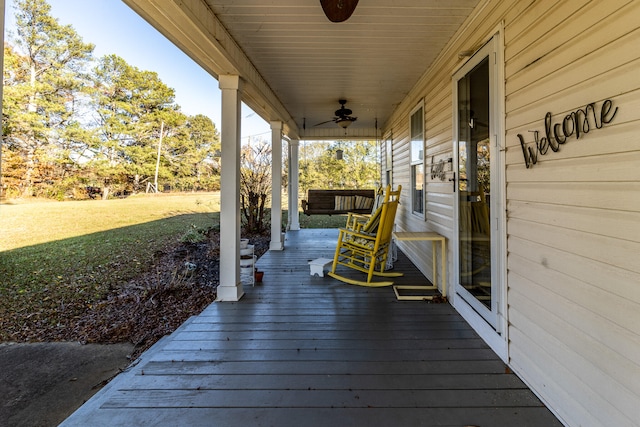 wooden deck featuring a lawn, ceiling fan, and covered porch