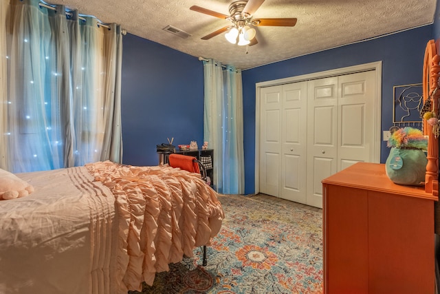 carpeted bedroom featuring ceiling fan, a textured ceiling, and a closet