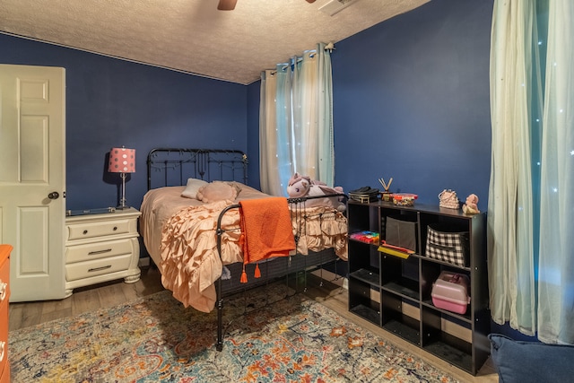 bedroom with hardwood / wood-style floors, ceiling fan, and a textured ceiling