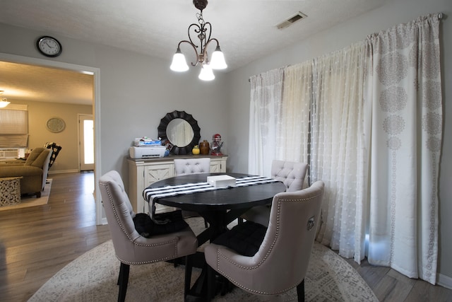 dining room with hardwood / wood-style floors, a textured ceiling, and a notable chandelier