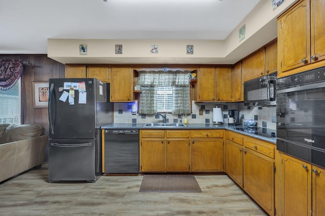 kitchen with black appliances, light hardwood / wood-style floors, sink, and tasteful backsplash