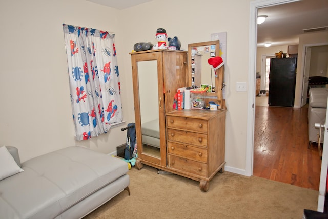 bedroom featuring black fridge and hardwood / wood-style flooring