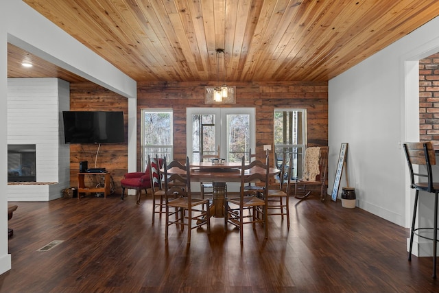 dining space featuring plenty of natural light, wood walls, and dark hardwood / wood-style floors