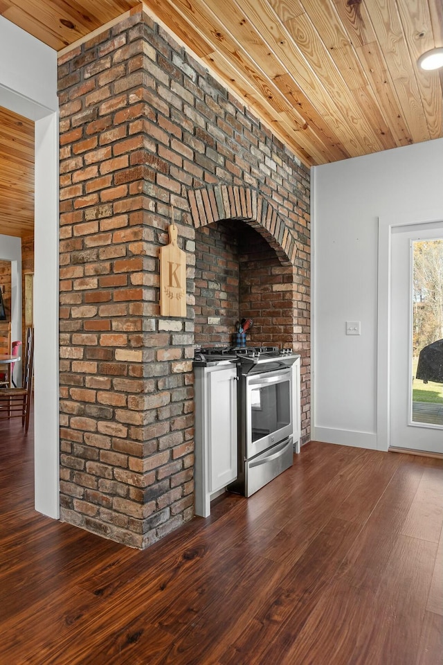 kitchen with stainless steel gas stove, dark hardwood / wood-style flooring, wooden ceiling, and brick wall