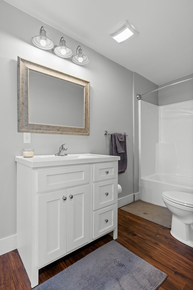 bathroom featuring hardwood / wood-style flooring, vanity, toilet, and a shower