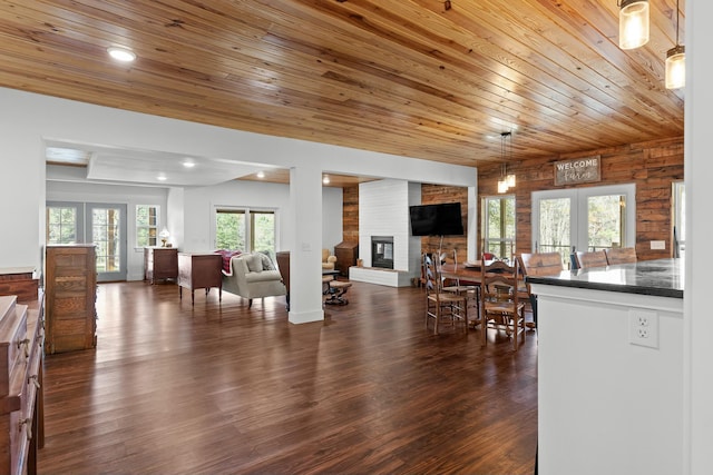 dining room featuring a fireplace, wooden ceiling, dark wood-type flooring, and french doors