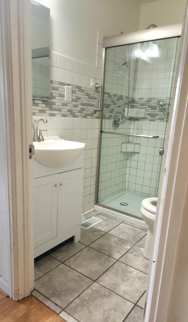 bathroom with vanity, toilet, an enclosed shower, and backsplash