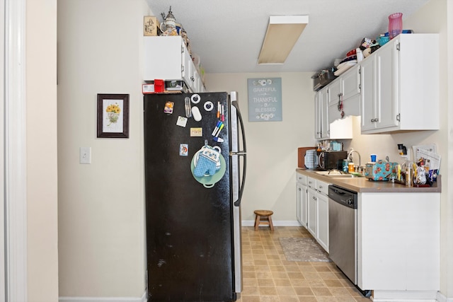 kitchen featuring black refrigerator, white cabinets, stainless steel dishwasher, and sink