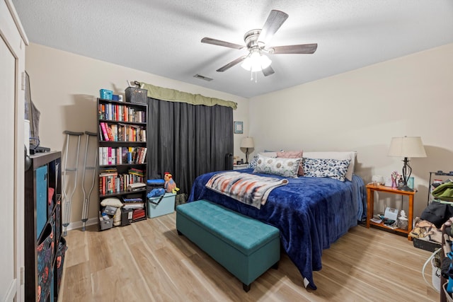 bedroom featuring ceiling fan, a textured ceiling, and light hardwood / wood-style flooring