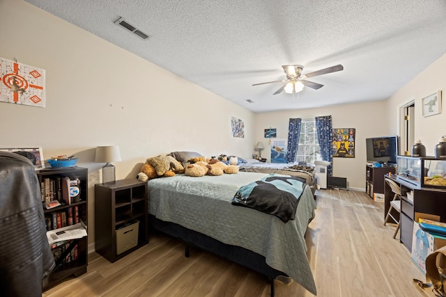 bedroom with ceiling fan, light wood-type flooring, and a textured ceiling