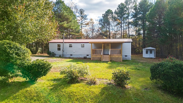 view of front of house with a porch, a front yard, and a storage shed