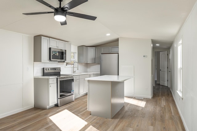 kitchen featuring appliances with stainless steel finishes, light hardwood / wood-style floors, sink, gray cabinets, and a kitchen island