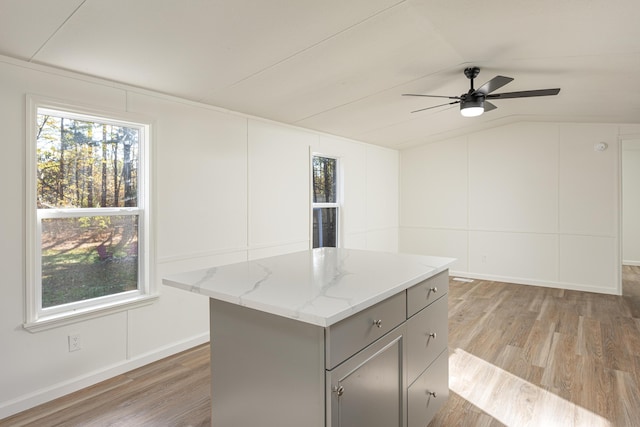 kitchen with plenty of natural light, a center island, vaulted ceiling, and light wood-type flooring