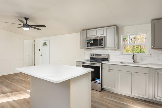 kitchen featuring ceiling fan, sink, light hardwood / wood-style flooring, a kitchen island, and appliances with stainless steel finishes