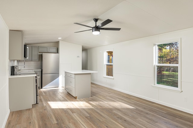 kitchen with a center island, backsplash, white fridge, gray cabinets, and light wood-type flooring