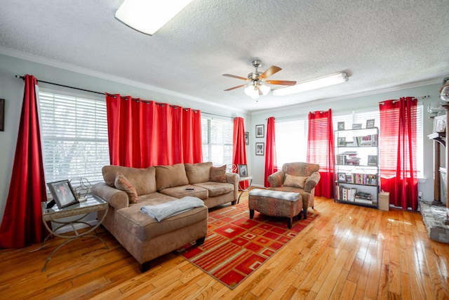 living room featuring wood-type flooring, a textured ceiling, ceiling fan, and crown molding