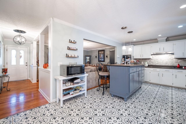 kitchen with white cabinetry, crown molding, pendant lighting, and a textured ceiling