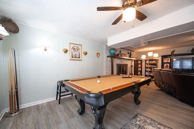 playroom with ceiling fan, wood-type flooring, a textured ceiling, a fireplace, and pool table