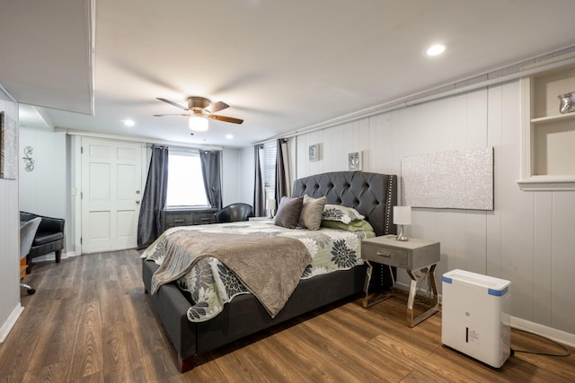 bedroom featuring wood walls, ceiling fan, and dark hardwood / wood-style floors