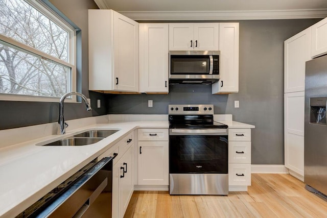 kitchen with sink, white cabinets, light hardwood / wood-style floors, and appliances with stainless steel finishes