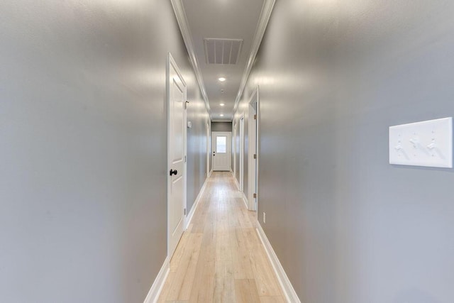 hall with light hardwood / wood-style floors and ornamental molding