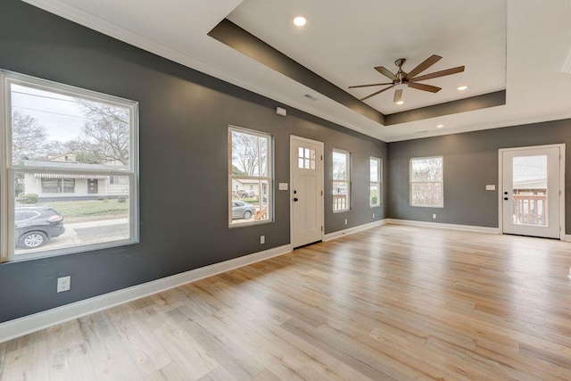 interior space with ceiling fan, light hardwood / wood-style floors, and a tray ceiling