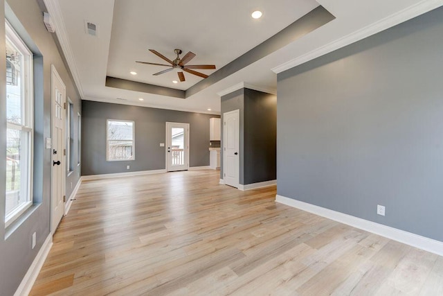 empty room with a tray ceiling, ceiling fan, and light hardwood / wood-style floors