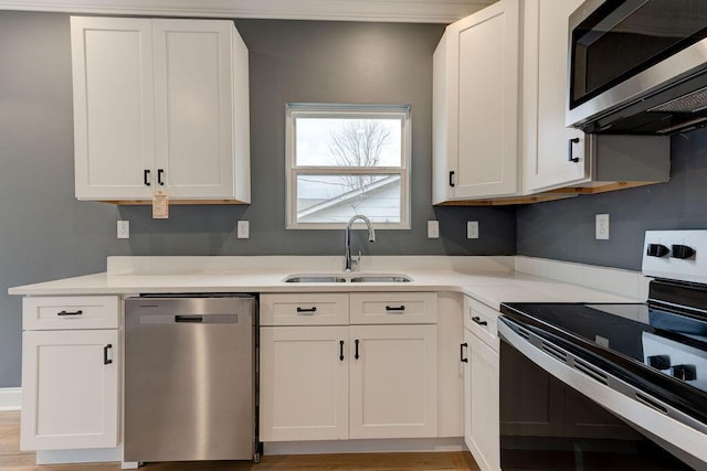 kitchen featuring white cabinets, light wood-type flooring, sink, and appliances with stainless steel finishes