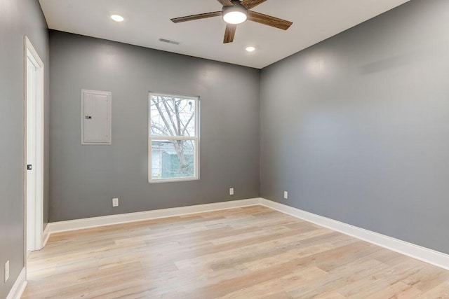 empty room with electric panel, ceiling fan, and light hardwood / wood-style floors