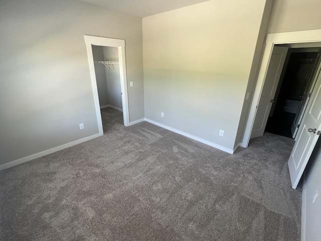 unfurnished bedroom with a walk in closet, dark carpet, and a closet