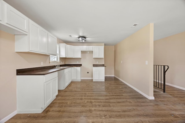 kitchen featuring hardwood / wood-style flooring, white cabinets, and sink