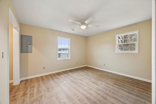 empty room with electric panel, ceiling fan, and light hardwood / wood-style flooring