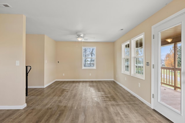 empty room with ceiling fan, a healthy amount of sunlight, and light hardwood / wood-style floors