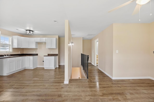 kitchen with light wood-type flooring, white cabinetry, ceiling fan, and sink