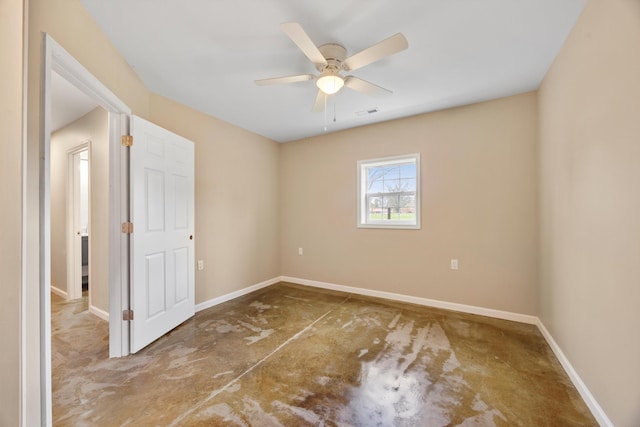 empty room with ceiling fan and concrete flooring