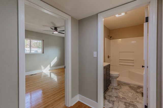 bathroom featuring vanity, a shower, hardwood / wood-style flooring, ceiling fan, and toilet