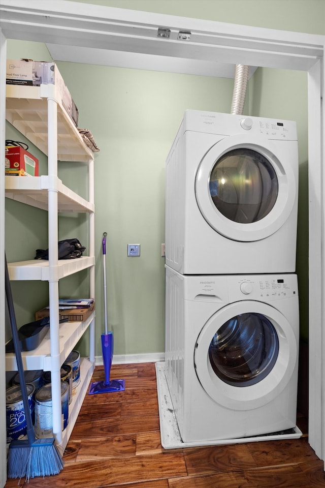 laundry room featuring dark hardwood / wood-style flooring and stacked washer / drying machine