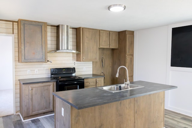 kitchen featuring a center island with sink, black electric range oven, wall chimney exhaust hood, and sink