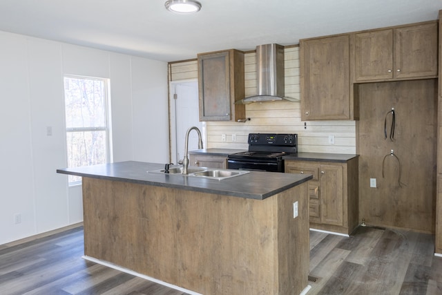 kitchen featuring electric range, wall chimney exhaust hood, a center island with sink, and sink